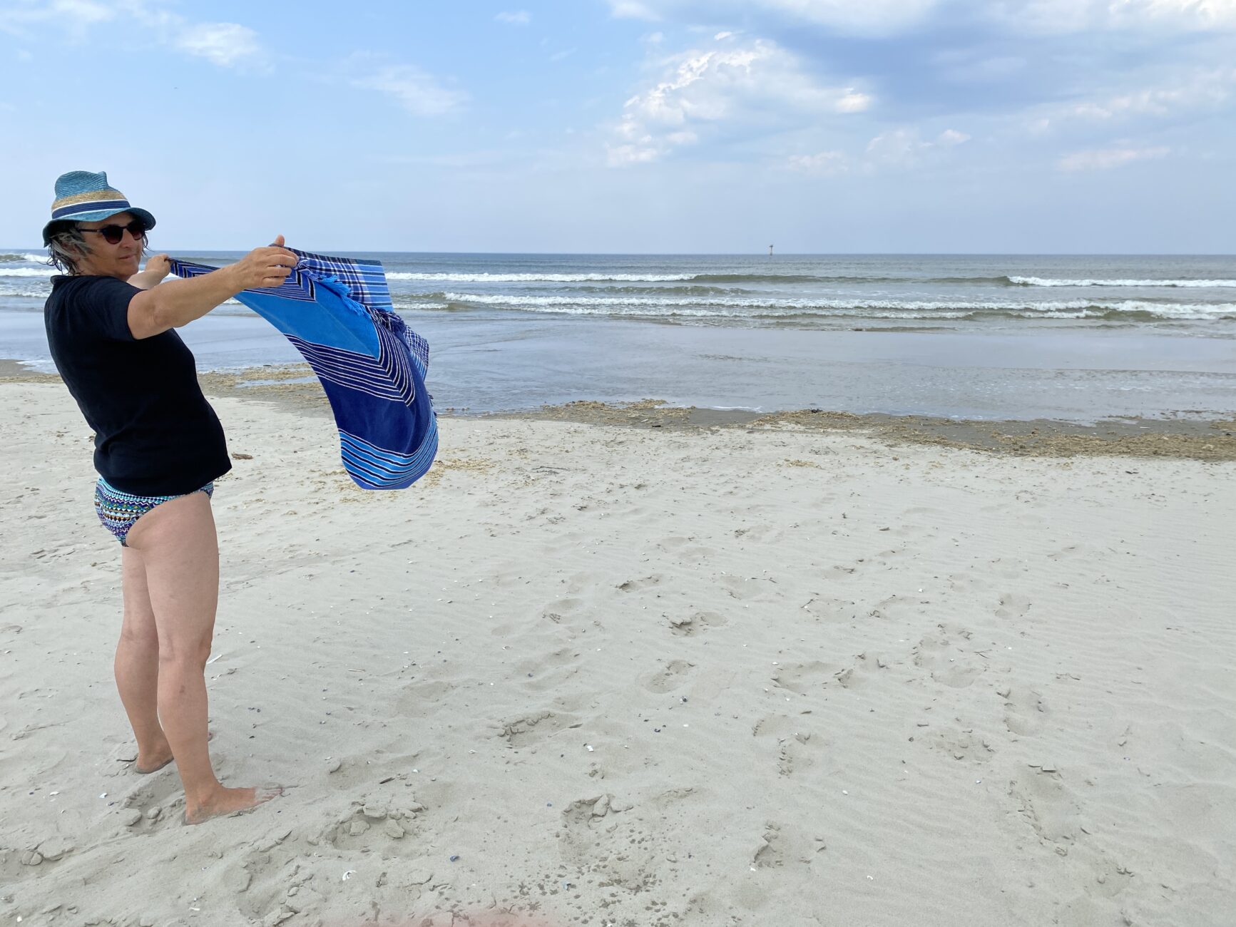 Frau hält Tuch am Strand