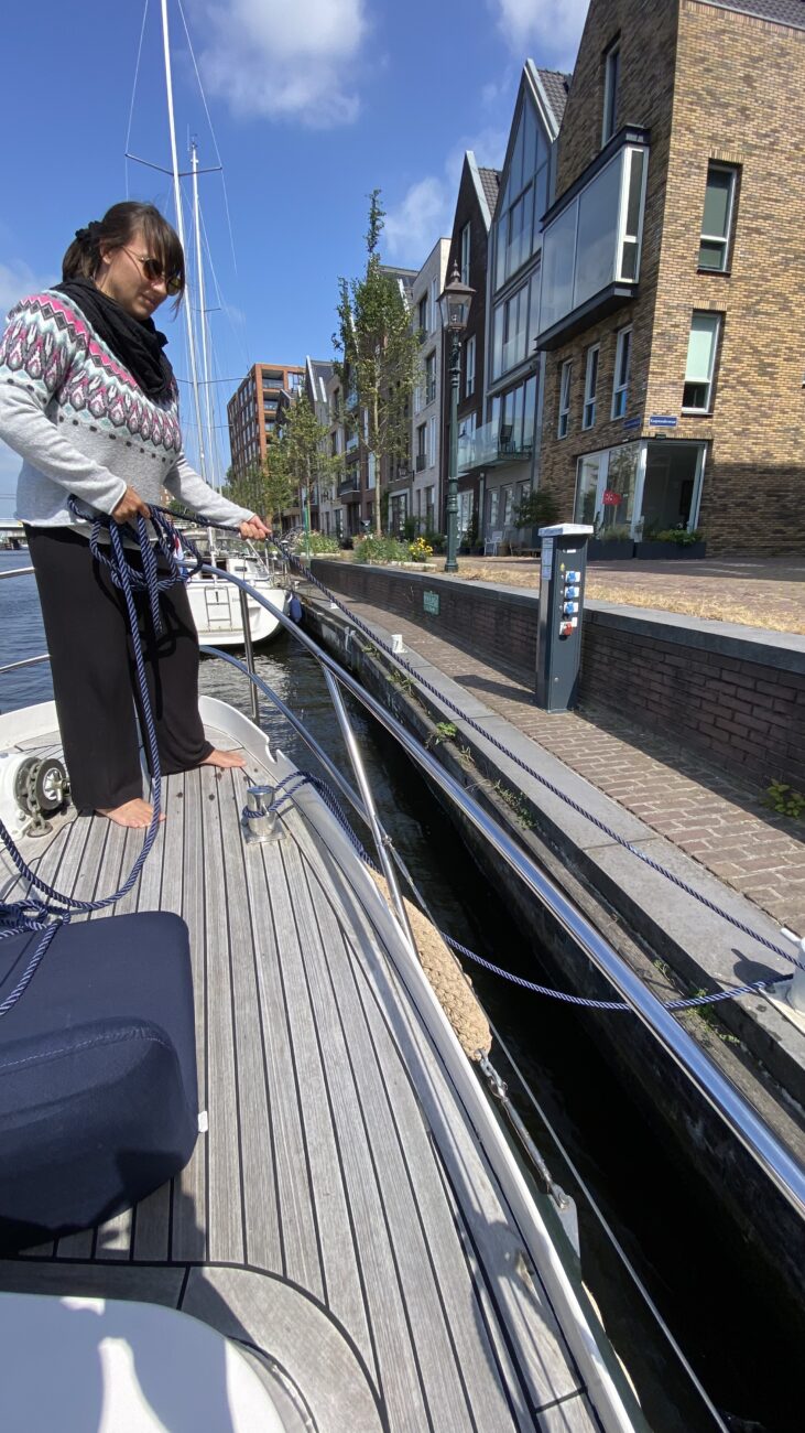 Frau hält mit Seil Schiff am Quai