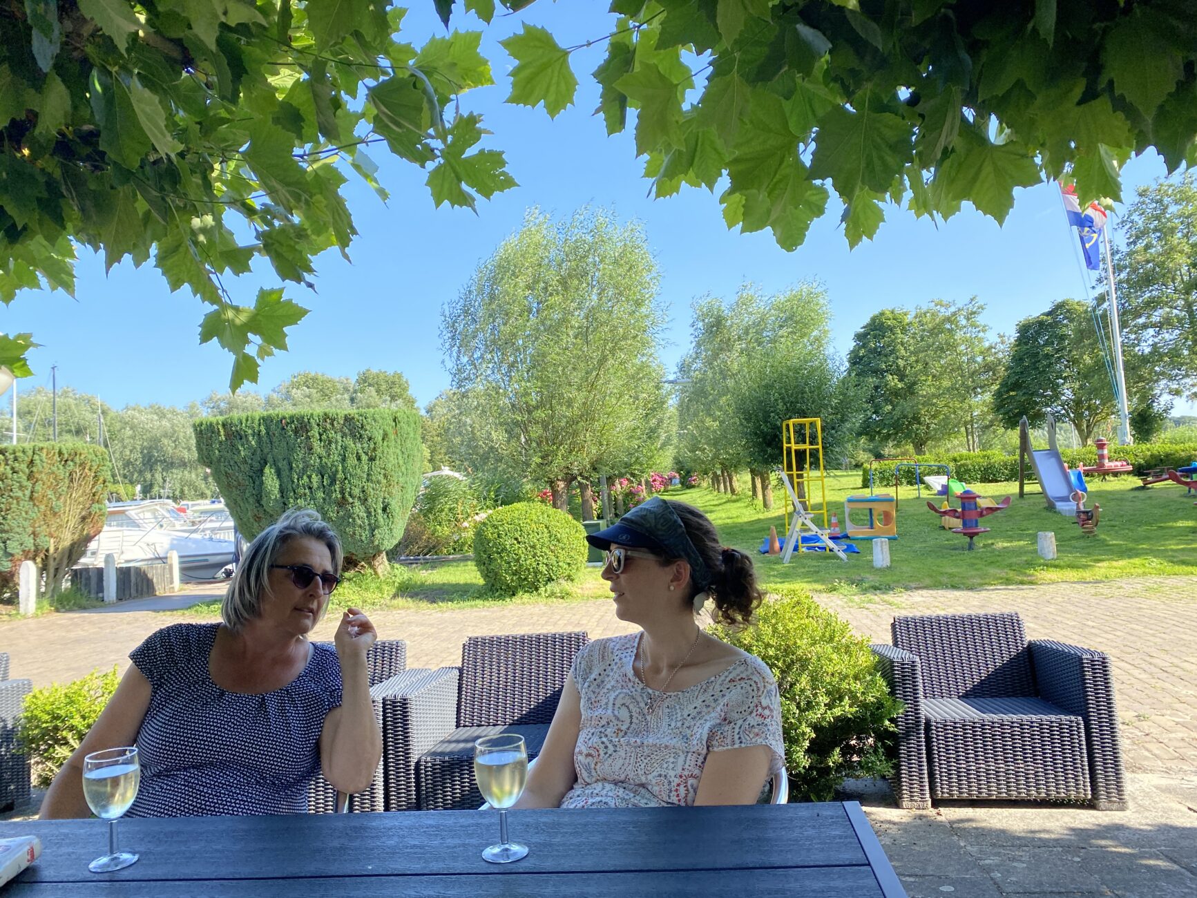 Zwei Frauen trinken am Tisch drausen Weisswein